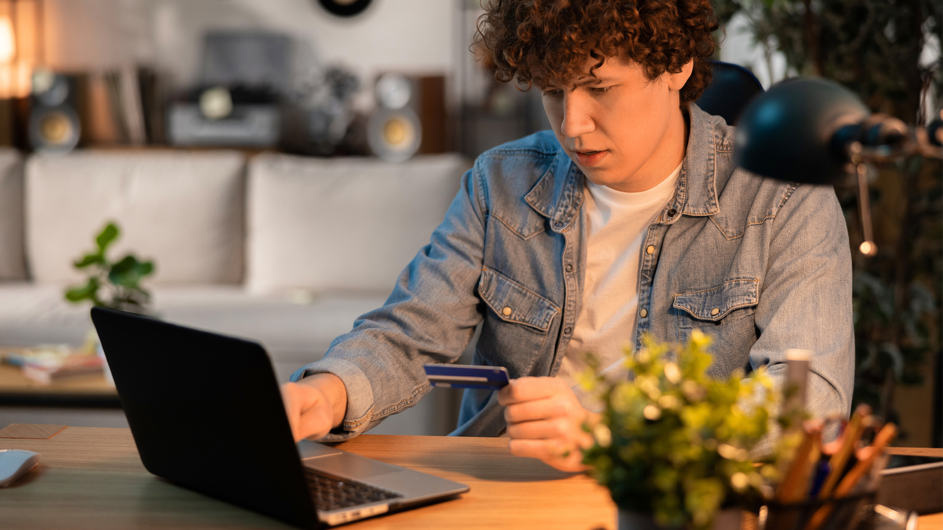 College age guy using credit card on laptop.