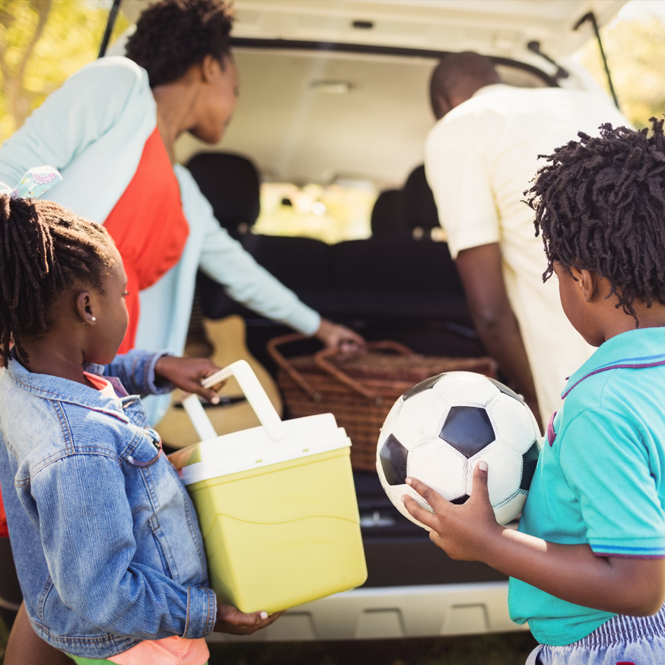 family getting summer things in car.